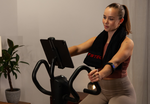 Frau während einer Cardio-Session auf dem Ergometer mit Tablet-Halterung S