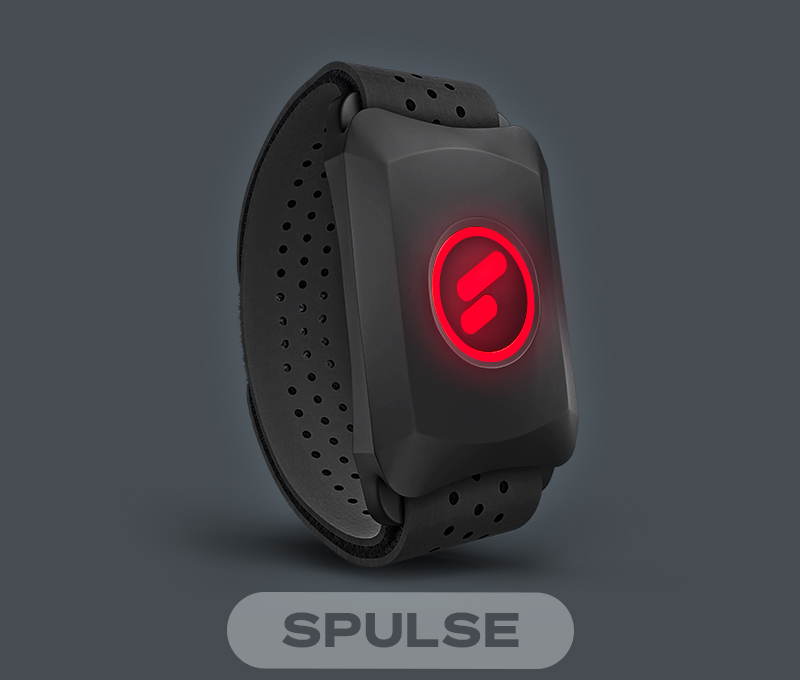 Tapis de course F10 noir plié, position verticale, à côté d’une table avec lampe et d’un canapé